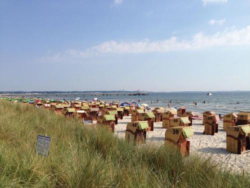 - une plage avec de nombreux parasols et des personnes dans l'eau dans l'établissement HAF OGa - Gästehaus Starke, à Haffkrug