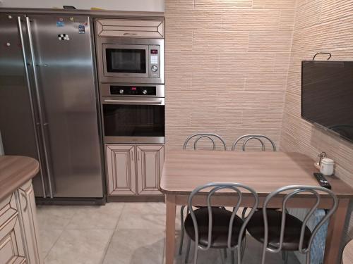a kitchen with a wooden table and a stainless steel refrigerator at Pokoje Jasionka Zaczernie in Trzebownisko