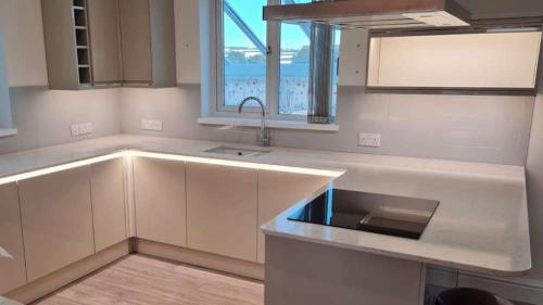a white kitchen with a sink and a window at Chymoresk - Self Catering Holiday Cottage Hayle St Ives Bay in Hayle