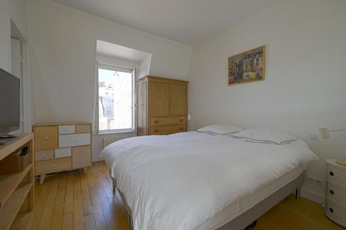 a bedroom with a bed and a dresser and a window at Rooftop Invalides in Paris