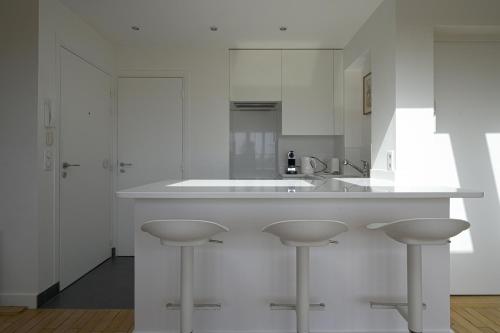 a white kitchen with a counter and two stools at Rooftop Invalides in Paris