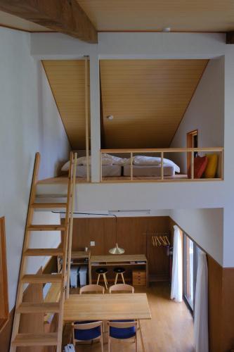 a loft bed in a room with a desk and a bed at ワタリグラスハウス in Gamō