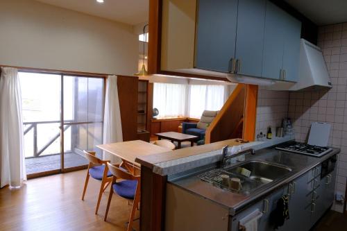 a kitchen with a sink and a table with chairs at ワタリグラスハウス in Gamō