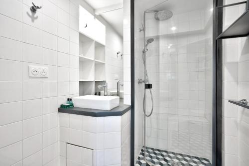 une salle de bain blanche avec un lavabo et une douche dans l'établissement Élégant T1 à 13 min du Musée du Louvre, à Paris