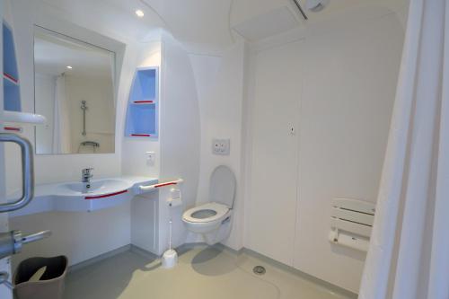 a white bathroom with a toilet and a sink at Camping Municipal Tindio in Arzon