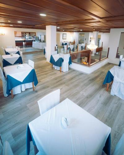 a dining room with white tables and blue chairs at Diana Hotel in Zakynthos Town