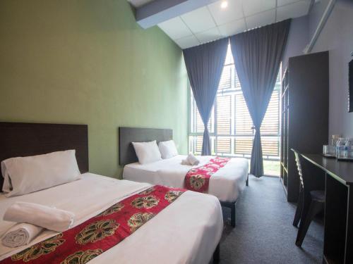a hotel room with two beds and a window at JQ BL Hotel, Ipoh in Ipoh