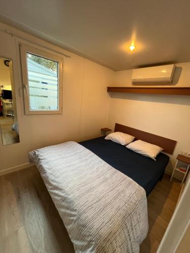 une petite chambre avec un lit et une fenêtre dans l'établissement Mobil-home Camping Oasis, à Roquebrune-sur Argens