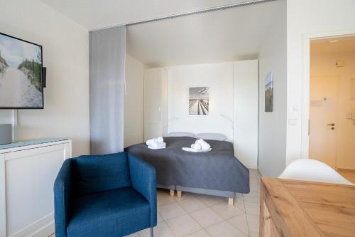 1 dormitorio con 1 cama y 1 silla azul en H3 53 - Hanseat - Außenschwimmbad, en Scharbeutz