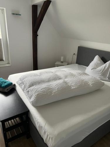 a bed with a white comforter on top of it at Woltorfer Landkrug in Peine