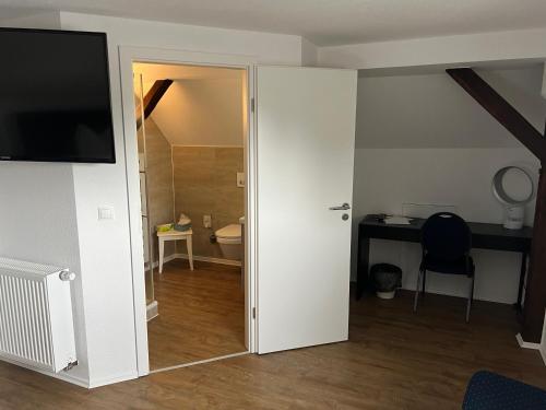 puerta abierta a un baño con aseo y escritorio en Woltorfer Landkrug en Peine