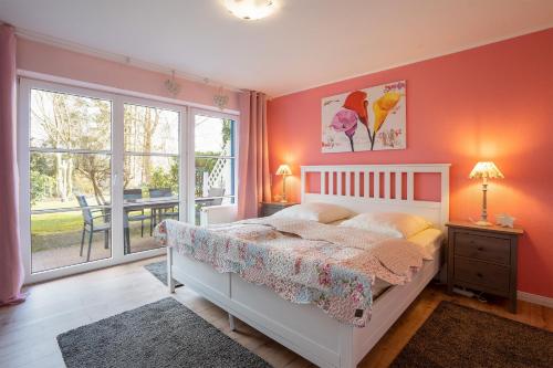 Un dormitorio con una cama con paredes rosas y una ventana en KON 003, en Scharbeutz