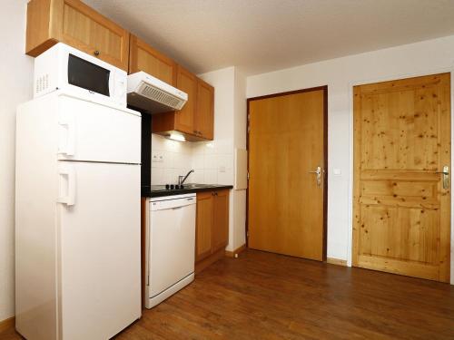 Una cocina con refrigerador blanco y gabinetes de madera. en A103- Appartement 2 pieces cabine 6 personnes, en Orcières
