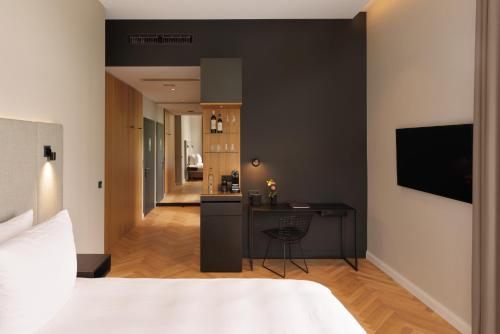 a bedroom with a bed and a desk and a kitchen at ESPLANADE Saarbrücken in Saarbrücken