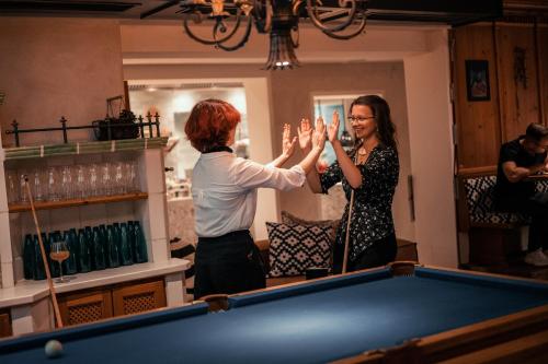 Duas mulheres estão a empilhar as mãos sobre uma mesa de bilhar. em Sendlhofer's em Bad Hofgastein