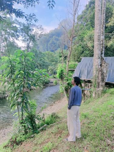 a woman standing on the side of a river at Khaosok August Freedom Camp in Khao Sok