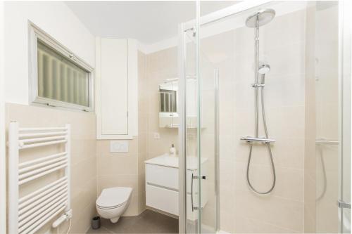 une salle de bain blanche avec douche et toilettes dans l'établissement COSY STUDIO - Résidence front de mer - Menton, à Menton