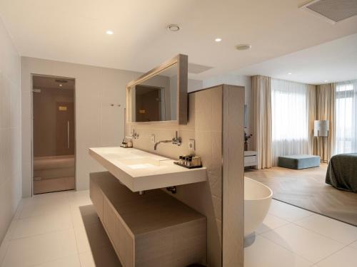a bathroom with a white sink and a tub at Van Der Valk Hotel Zwolle in Zwolle