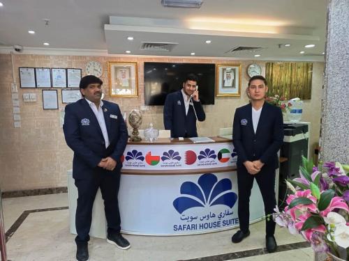 three men in suits standing in front of a counter at Safari House Suite in Kuwait