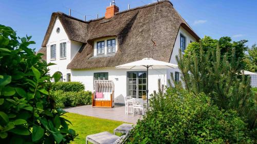 a white house with a thatched roof and a patio at Hus Andersen in Nieblum