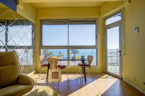 un salon avec une table, des chaises et des fenêtres dans l'établissement Maison Bianchi - 187 Promenade des Anglais - Sea view, à Nice