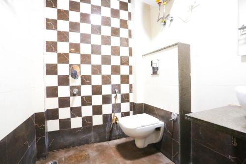 a bathroom with a checkered wall and a toilet at Hotel Aashiyana New Delhi in New Delhi