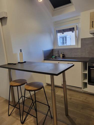 une cuisine avec une grande table et deux tabourets dans l'établissement Appartement COSY proche de Paris, à Chambourcy