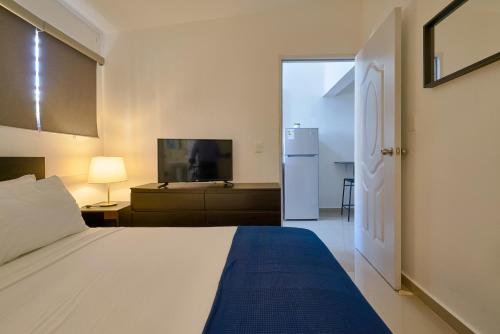 a bedroom with a white bed and a refrigerator at Escape Studio Close to Agora Mall in Santo Domingo
