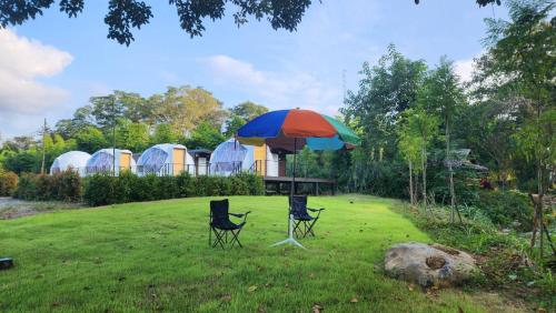 una mesa y dos sillas bajo una sombrilla en un patio en River hill khaoyai camping, en Pong Talong