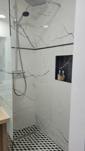 La salle de bains est pourvue d'une douche et de murs en marbre blanc. dans l'établissement Appartement COSY proche de Paris, à Chambourcy