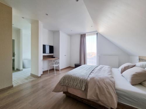 a white bedroom with a large bed and a window at Les Arbres sous le vent à 10 min de Pairi Daiza in Jurbise