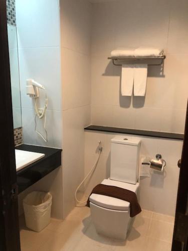 a bathroom with a toilet and a sink with towels at Vogue Pattaya Hotel in Pattaya Central