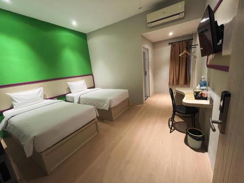 SukaramiにあるRuma Ruma Hotel Kenten - Palembangの緑の壁の客室で、ベッド2台が備わります。