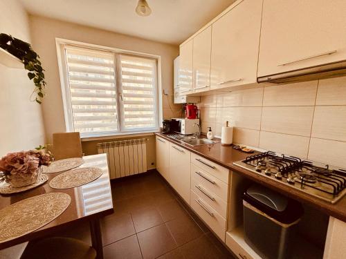 a kitchen with white cabinets and a table and a window at Sweet Apartament in Baia Mare