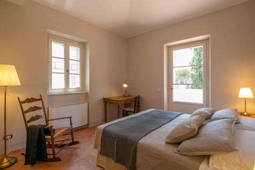 a bedroom with a bed and a chair and two windows at La piccola Severina in Cortona