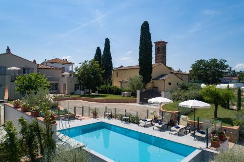 a pool with chairs and umbrellas in front of a building at La piccola Severina in Cortona