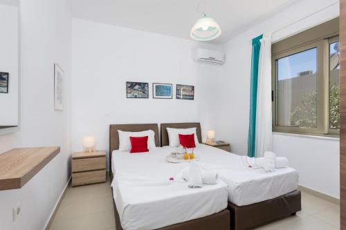 LitsárdhaにあるVilla Litsaの白い壁と赤い枕が備わる客室のベッド2台