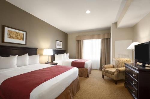 a hotel room with two beds and a flat screen tv at Country Inn & Suites by Radisson, Oklahoma City - Quail Springs, OK in Oklahoma City