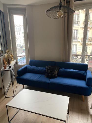 een blauwe bank in een woonkamer met een groot raam bij Bel Appartement 2 pièces à Neuilly Porte Maillot ! in Neuilly-sur-Seine