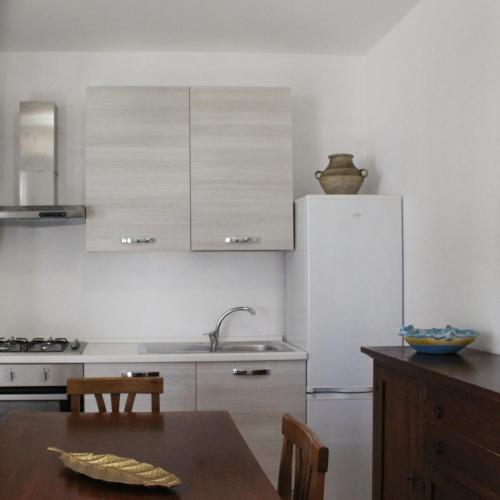 a kitchen with a white refrigerator and a table at Villa Dei Lidi - HomeSalento com in Torre San Giovanni Ugento