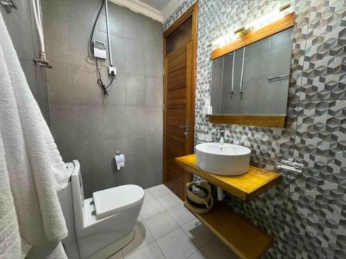 een badkamer met een wit toilet en een wastafel bij Nzuri Nest -Queen in Kigali