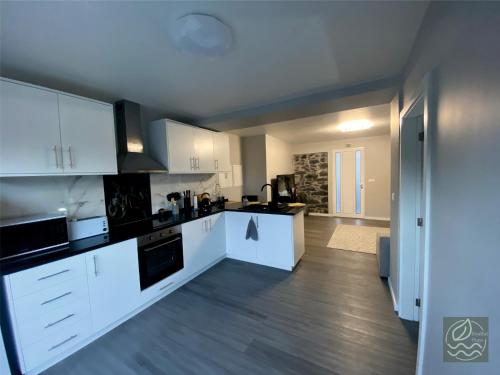 eine Küche mit weißen Schränken und Geräten in einem Zimmer in der Unterkunft My Little Home Cottage 2 Bedrooms - Soulful Stays in Porto Moniz