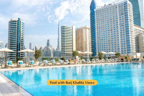 a pool with chairs and umbrellas in a city at The First Collection Business Bay in Dubai