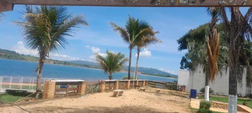 una playa con palmeras y un cuerpo de agua en Rancho dos Deuses en Guapé
