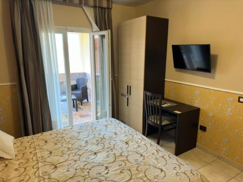 Dormitorio con cama, escritorio y TV en Hotel De La Ville Relais, en Fiumicino