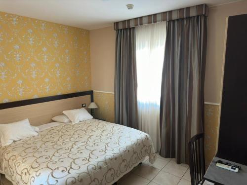 a bedroom with a bed and a window at Hotel De La Ville Relais in Fiumicino