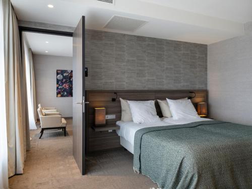 a bedroom with a large bed and a chair at Van Der Valk Hotel Zwolle in Zwolle