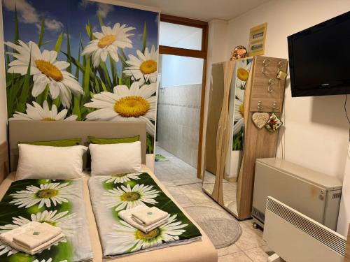 a room with two beds with flowers on the wall at Nela Apartmani in Niš
