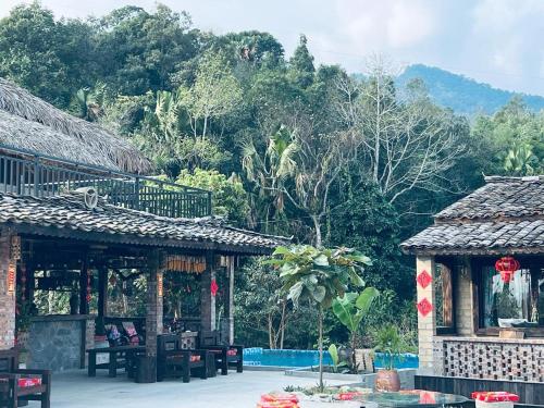 a building with tables and chairs in front of a forest at Local Ban Bang Homestay - Motorbike rental and Tour in Ha Giang