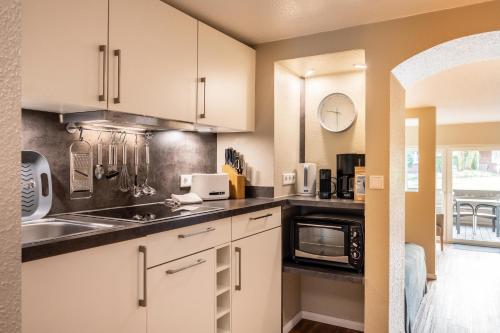 een keuken met witte kasten, een wastafel en een magnetron bij Riff5 Wohnung 1 in Borkum